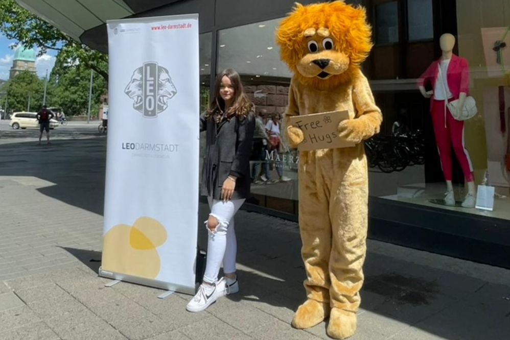 Unser Maskottchen Leo (Paul) mit unserem Mitglied Laura und dem Leo-Roll-Up am weißen Turm